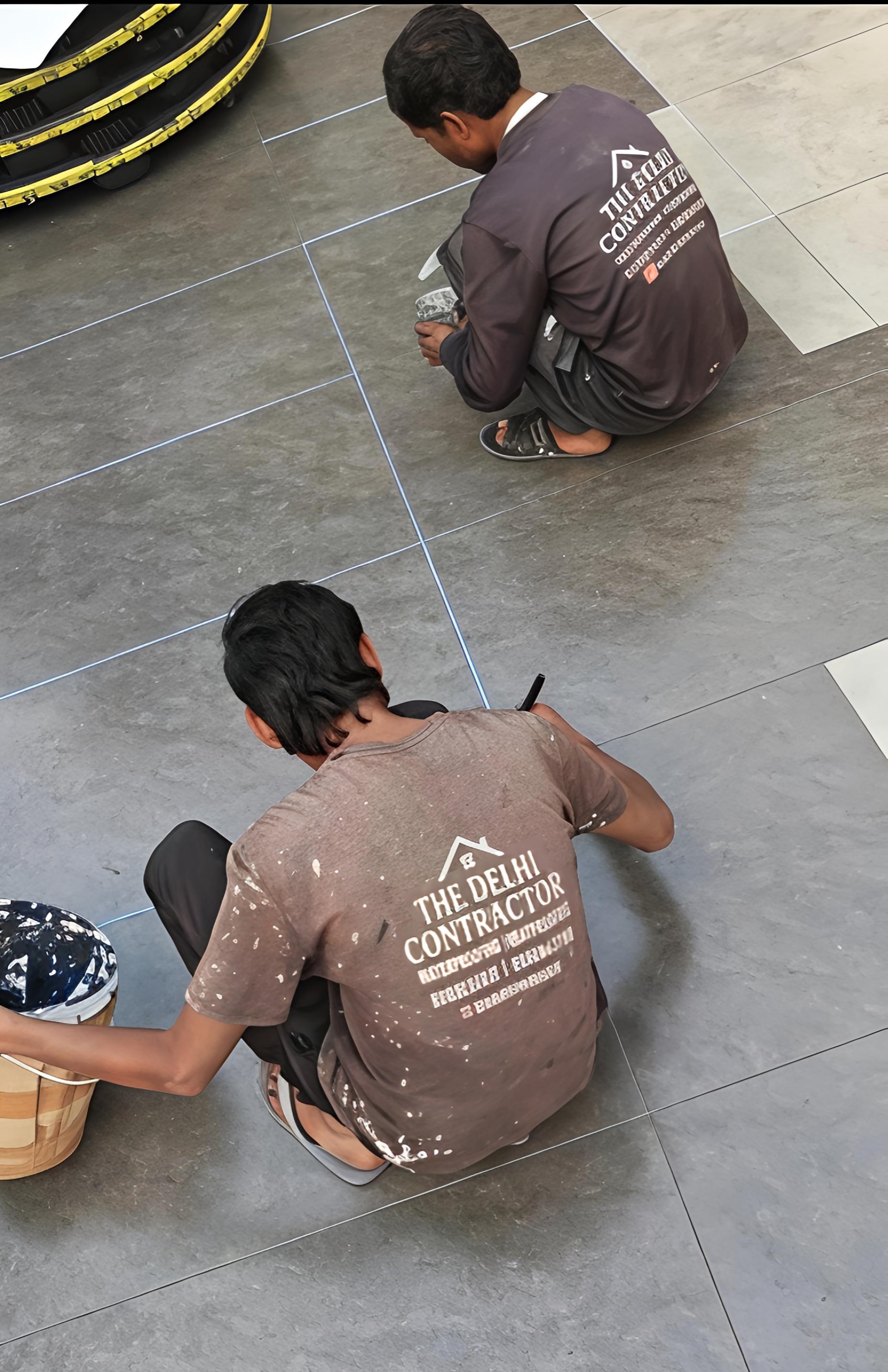 Applicator in a branded The Delhi Contractor shirt applying the BlackCoat membrane layer of the 7-layer system on a Sainik Farm roof.