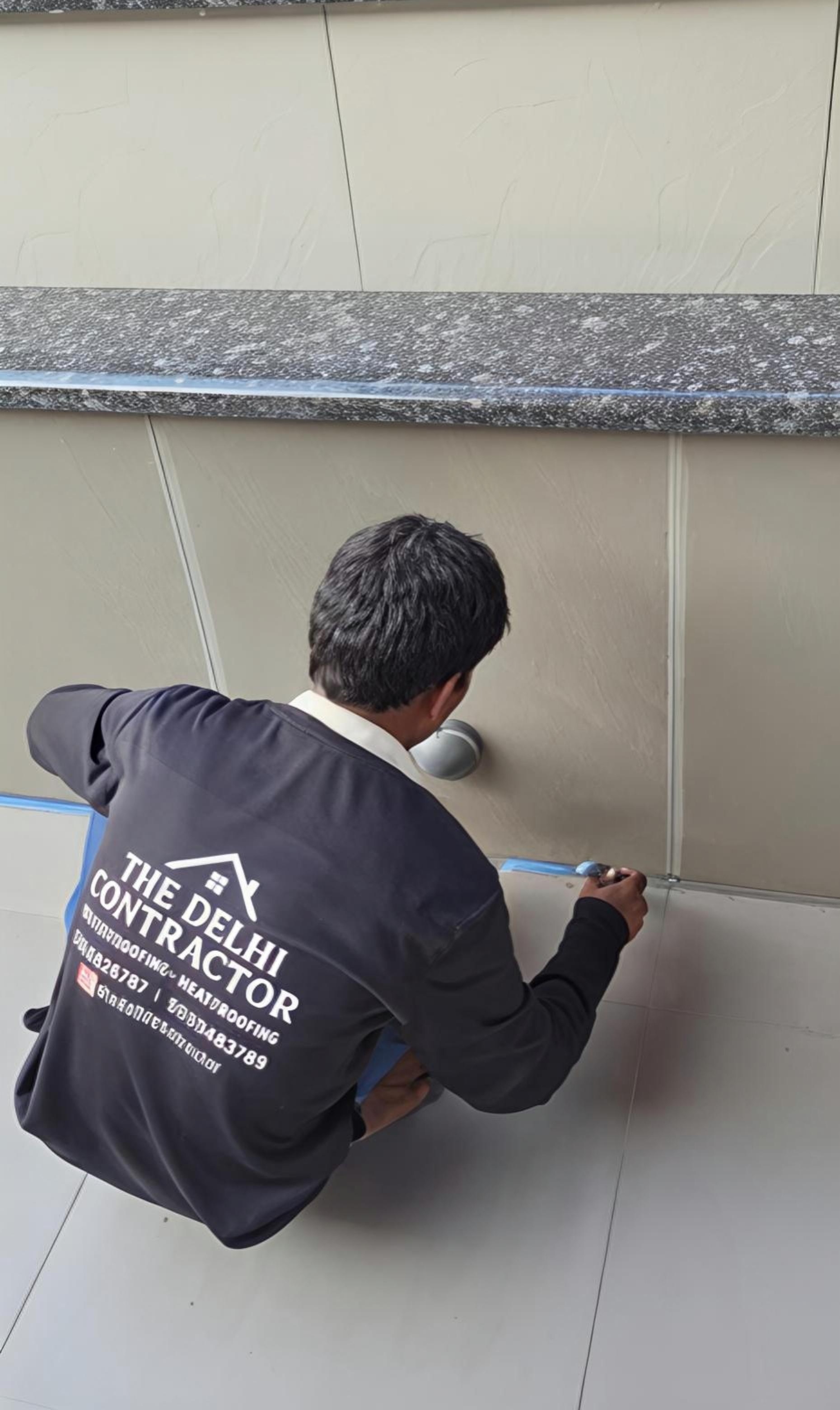 Team member applying clear transparent waterproofing over existing roof tiles at a Lajpat Nagar home — no tiles broken or replaced.