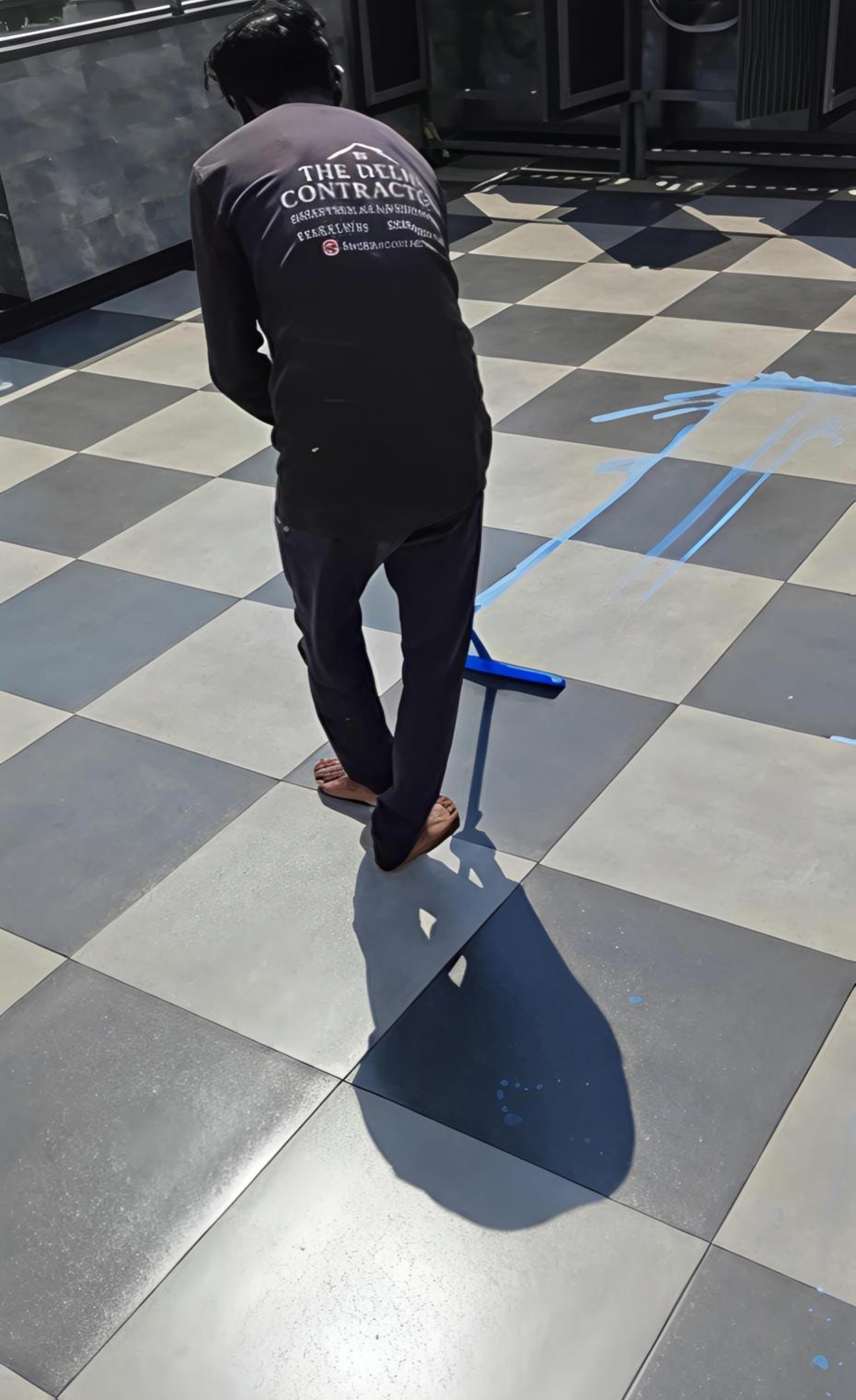 Worker in The Delhi Contractor uniform coating a Palam Vihar terrace with transparent 5-layer waterproofing.