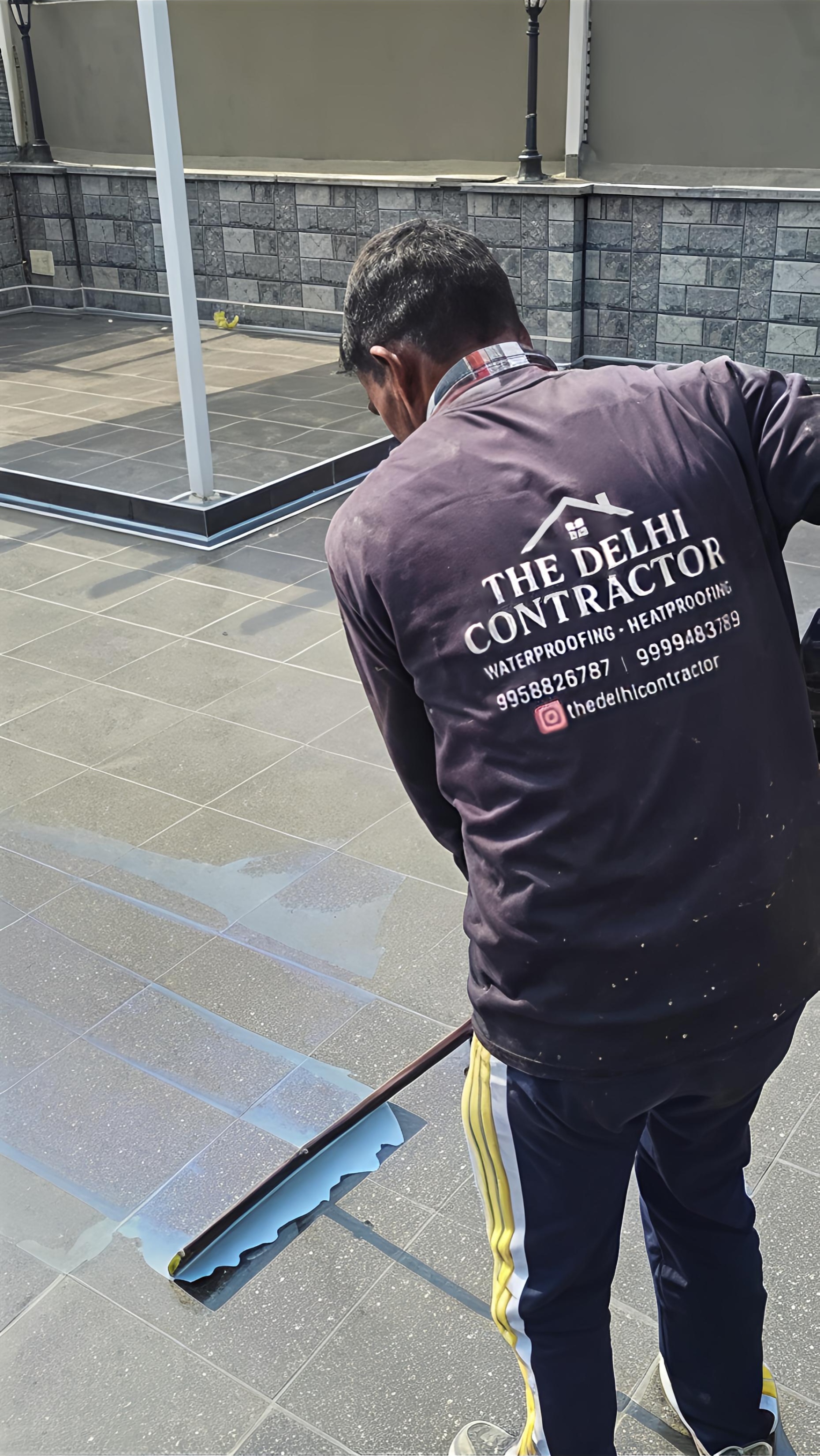 Applicator coating a Rajouri Garden rooftop terrace with the transparent 5-layer waterproofing system.