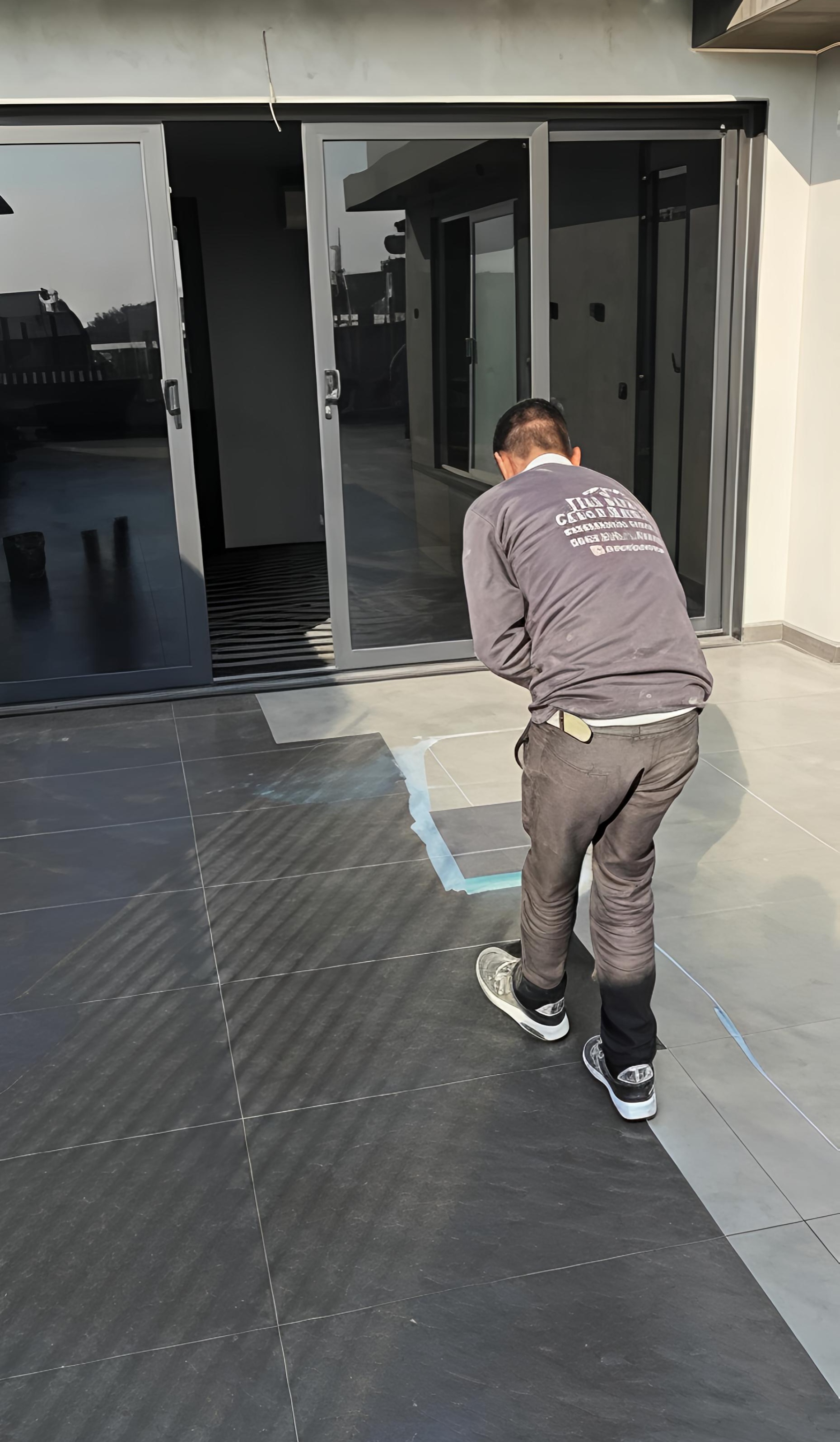 Transparent 5-layer waterproofing application in progress on a South Ex terrace by a uniformed team member.